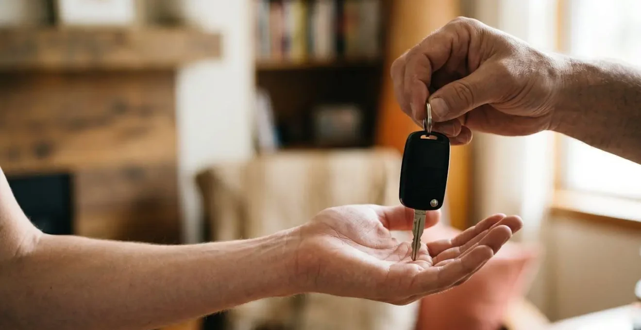 Jeune adulte recevant les clés d'une voiture de la main d'un parent dans un cadre familial